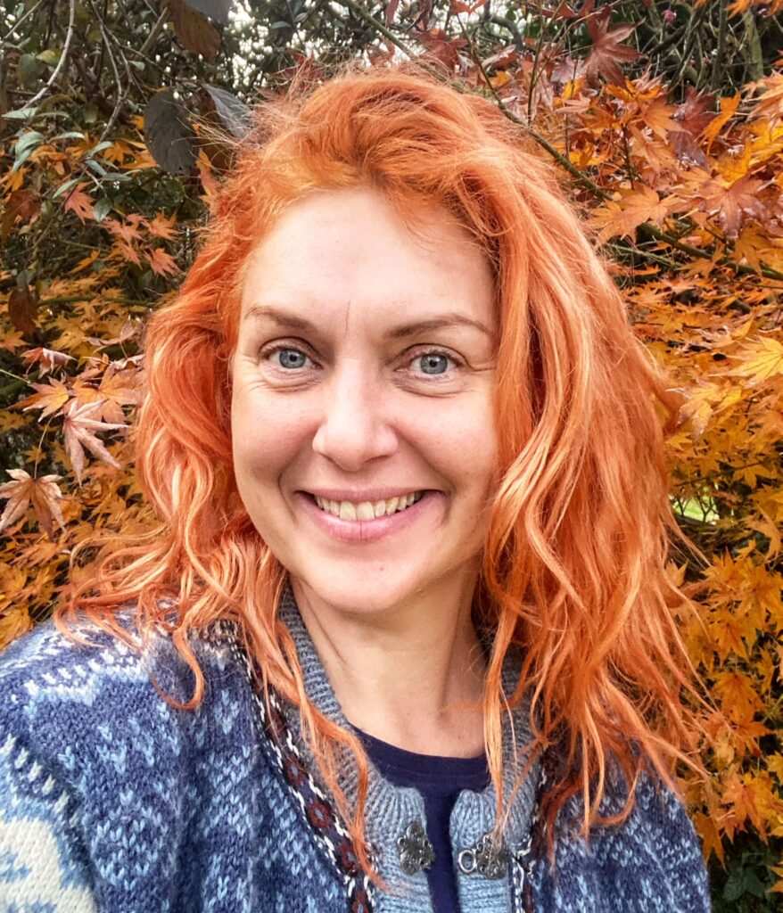 Laura King stands amongst the autumn colours, smiling.